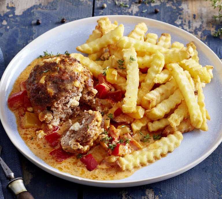 Mini-Braten in Paprika-Rahm auf einem weißen Teller auf dunkelblauem Hintergrund. | © EAT CLUB/Isabell Triemer