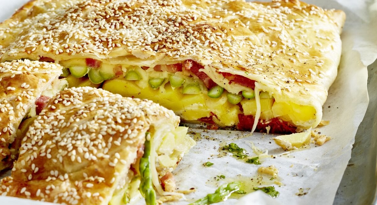 Käse-Tomaten-Tarte auf einem silbernen Blech mit weißem Backpapier.