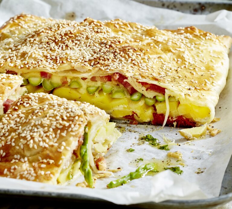 Käse-Tomaten-Tarte auf einem silbernen Blech mit weißem Backpapier. | © EAT CLUB/Isabell Triemer