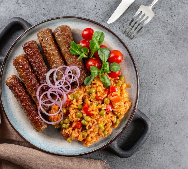 Djuvec-Reis mit Cevapcici auf Teller.  | © AdobeStock/Olga