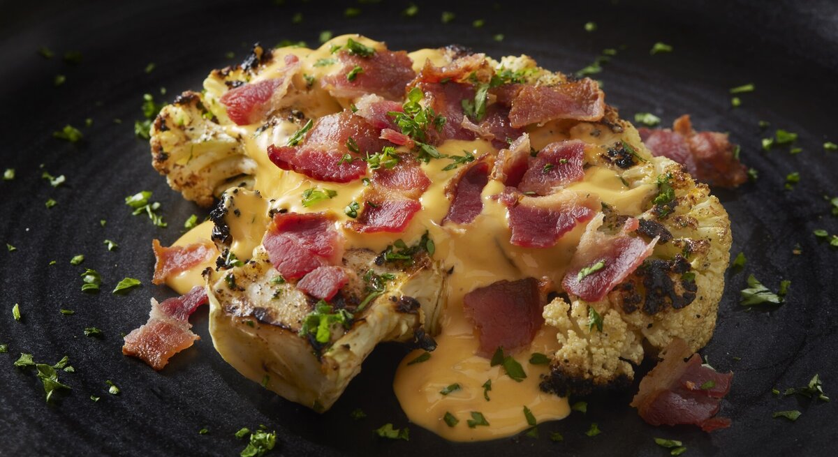 Blumenkohl-Steak mit Käsesoße und Schinken.